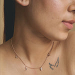 Rose gold celestial charm necklace with star, moon, and delicate dangling charms on a fine chain