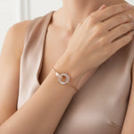 Minimal rose gold bracelet with intertwined circular charm and baguette crystal detailing on a delicate chain.