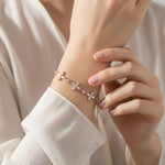 Rose gold floral charm bracelet with delicate flower motifs and sparkling crystal accents on a fine chain.