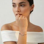 Rose gold bracelet with butterfly charm, blue evil eye accent, and infinity symbol on delicate chain bracelet design.