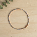 Elegant rose gold tennis bracelet with sparkling crystal stones on a minimal