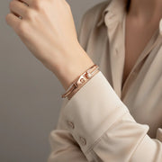 Rose gold bracelet with dual charms and stone-studded band design