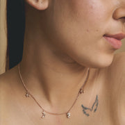 Rose gold celestial charm necklace with star, moon, and delicate dangling charms on a fine chain