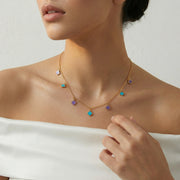 Gold chain necklace with pastel clover charms in turquoise and lilac tones, minimal elegant design for everyday wear.