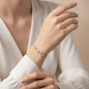 Elegant blush rose gold bracelet with crystal studded charms and geometric links on a fine adjustable chain.