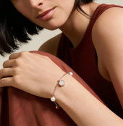 Minimal rose gold bracelet with pearl charms and geometric accents on a delicate chain design.