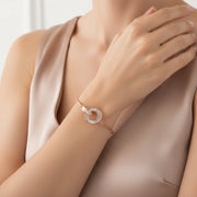 Minimal rose gold bracelet with intertwined circular charm and baguette crystal detailing on a delicate chain.
