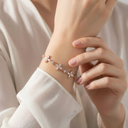 Rose gold floral charm bracelet with delicate flower motifs and sparkling crystal accents on a fine chain.