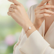 Rose gold floral bracelet with white flower charm and crystal accents on a delicate chain.