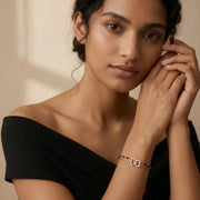 Rose gold bracelet with black bead accents and intertwined crystal heart charms on a delicate chain.