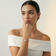 Minimal silver bracelet with white clover charm and crystal accent on a delicate chain.