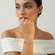Rose gold bracelet with butterfly charm, blue evil eye accent, and infinity symbol on delicate chain bracelet design.