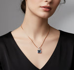 Elegant rose gold pendant necklace featuring a rectangular blue gemstone with crystal floral accents