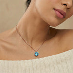 Rose gold necklace with blue geometric crystal pendant on a minimal chain design.
