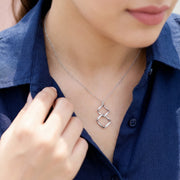 Minimal geometric linked square necklace with crystal accents in a modern silver finish on a delicate chain.
