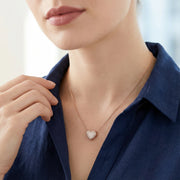 Rose gold pave heart pendant necklace with sparkling stones on a delicate chain against a soft
