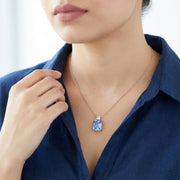 Elegant rose gold necklace featuring a sparkling blue rectangular crystal pendant with a delicate clear stone detail on a fine chain.
