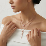 Rose gold dual layer necklace with sleek vertical bar pendant and sparkling circular charm on box chain design.

