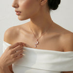 Rose gold crescent moon pendant necklace with crystal stones and dangling teardrop charm on a delicate chain.
