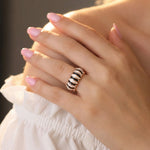 Rose gold striped enamel band ring with black and white detailing on a polished modern statement design.
