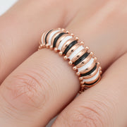 Rose gold striped enamel band ring with black and white detailing on a polished modern statement design.
