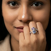 Elegant dual heart crystal ring with purple and blue gemstones surrounded by sparkling crystals on a silver finish band.
