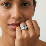 Elegant ocean blue emerald cut crystal ring with sparkling side stones and silver finish for women
