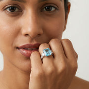 Elegant ocean blue emerald cut crystal ring with sparkling side stones and silver finish for women
