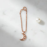 Rose gold crescent moon charm with sparkling crystal accents and chain attachment
