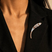 Rose gold chevron brooch pin with sparkling crystal detailing and iridescent shell inlay in a sleek curved design.
