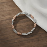 Dual tone filigree link bracelet with rose gold and silver finish featuring intricate cutwork pattern and modern elegant design for women.
