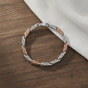Dual tone filigree link bracelet with rose gold and silver finish featuring intricate cutwork pattern and modern elegant design for women.
