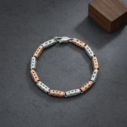 Rose gold and silver dual tone barrel link bracelet with geometric cut detailing and polished finish for women.
