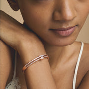Rose gold open cuff bracelet with oval crystal centerpiece and pavé stone detailing
