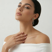 Elegant emerald halo hoop earrings with green gemstone studs and crystal detailed silver hoops for women.

