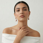 Rose gold mosaic drop earrings with white, red, and black enamel detailing on a sleek hoop design.
