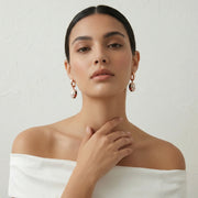 Rose gold mosaic drop earrings with white, red, and black enamel detailing on a sleek hoop design.
