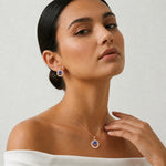 Rose gold sapphire halo pendant and earrings jewellery set with sparkling blue centre stones and crystal detailing.
