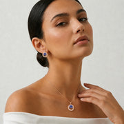 Rose gold sapphire halo pendant and earrings jewellery set with sparkling blue centre stones and crystal detailing.

