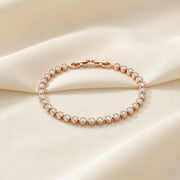 Rose gold crystal tennis bracelet with round bezel-set stones and elegant luxury design for women.
