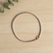 Elegant rose gold tennis bracelet with sparkling crystal stones on a minimal
