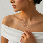 Elegant blush butterfly drop necklace in rose gold tone with crystal stones and dangling butterfly charms on a delicate chain.
