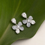 Floral earrings with clear stones on a green leaf